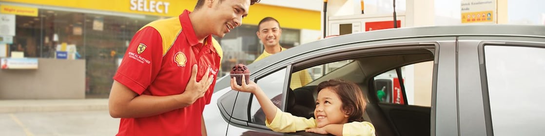 Shell station attendant receiving a muffin from a girl.