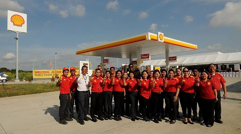 people standing near shell station for photo