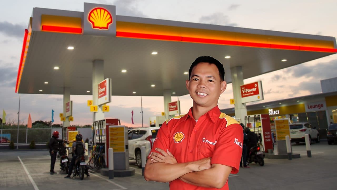man standing in front of Shell station with folded hands and smiling