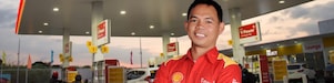 man standing in front of Shell station with folded hands and smiling