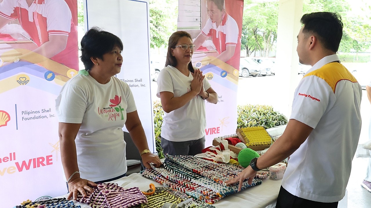 Powering Lives page showing two men and a woman in front of a table