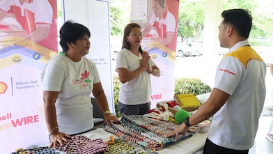 Powering Lives page showing two men and a woman in front of a table